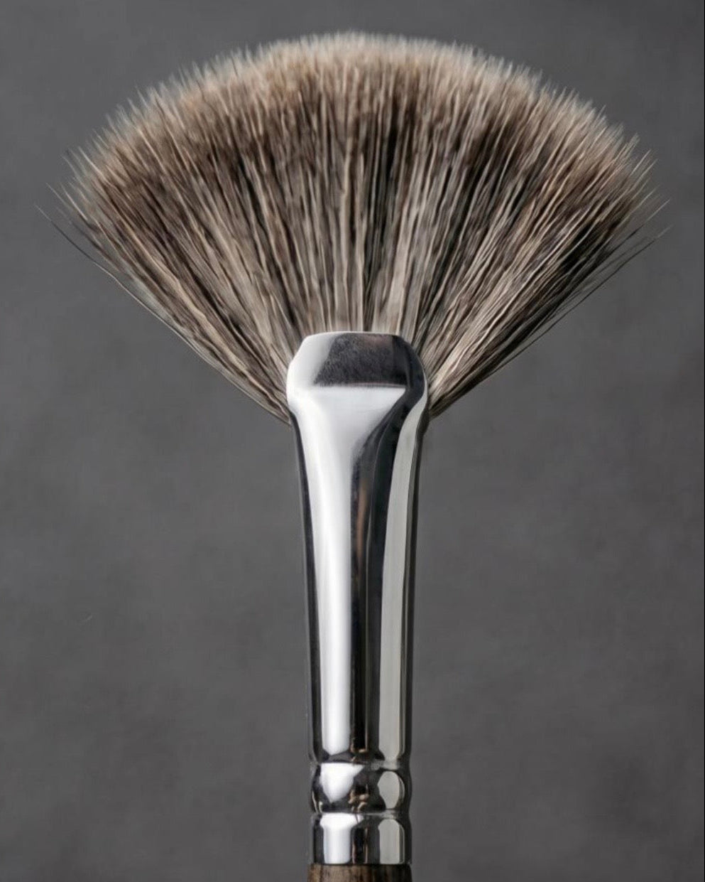 A close-up studio shot of a makeup brush with soft bristles in a warm taupe-brown and beige gradient, a polished silver metal ferrule, and a dark brown wooden handle, set against a dark gray background.

Close-up of brush head showing densely packed ultra-soft bristles. Text: ‘100% premium ultra-soft hair — Hypoallergenic, ideal for sensitive skin’. Fine quality fibres, gentle texture, luxurious finish.