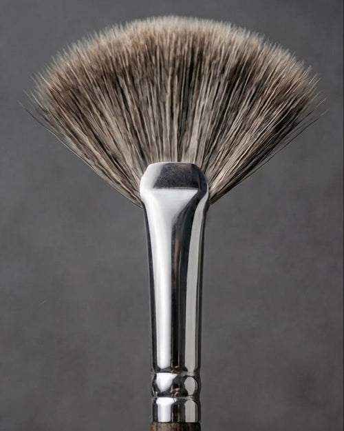 A close-up studio shot of a makeup brush with soft bristles in a warm taupe-brown and beige gradient, a polished silver metal ferrule, and a dark brown wooden handle, set against a dark gray background.

Close-up of brush head showing densely packed ultra-soft bristles. Text: ‘100% premium ultra-soft hair — Hypoallergenic, ideal for sensitive skin’. Fine quality fibres, gentle texture, luxurious finish.